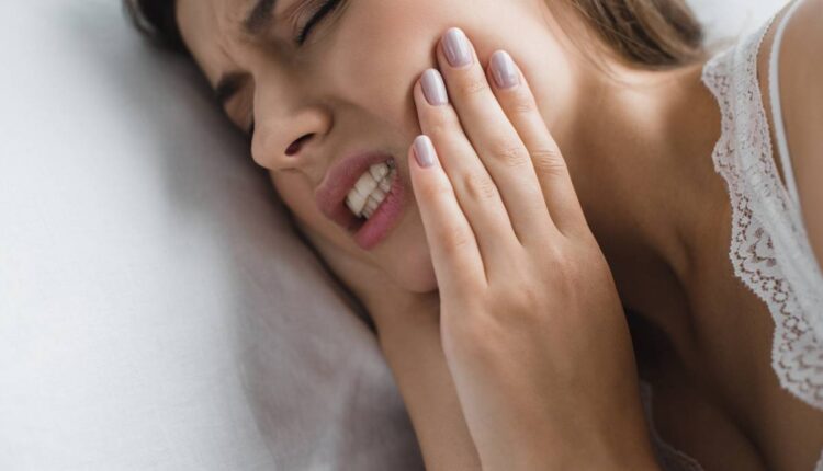 close-up view of young woman suffering from toothache while lying in bed