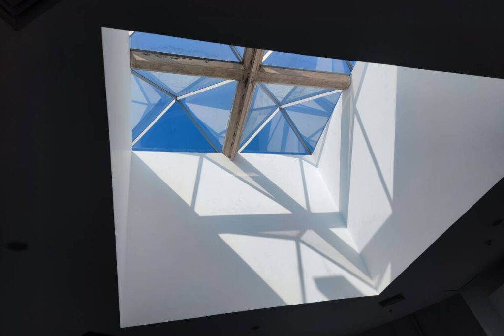 A low angle shot of a small wooden window in the ceiling of a black and white interior house