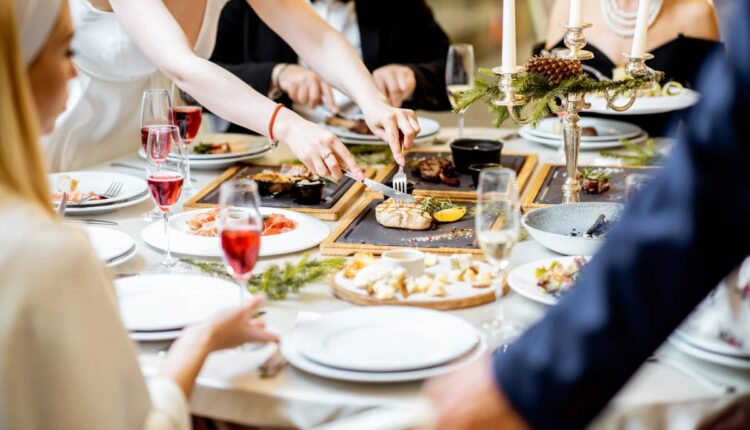 People having a festive dinner at a well-served table with tasty dishes during New Year Eve at the luxury restaurant, close-up view with no face