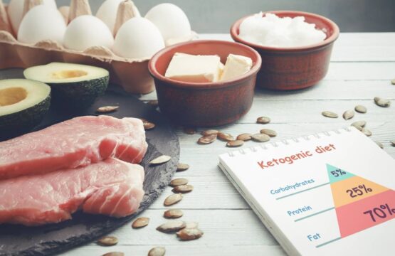 Concept of ketogenic diet. Dietary food and notepad with infographic on light table.